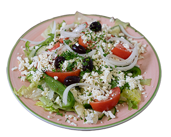plate of green lettuce, sliced cucumbers, sliced tomato wedges, black olives, sliced white onions, crumbled feta cheese and homemade Greek dressing.